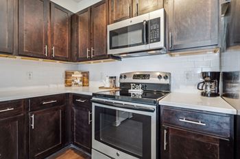 A kitchen with dark wood cabinets and a stove top oven.